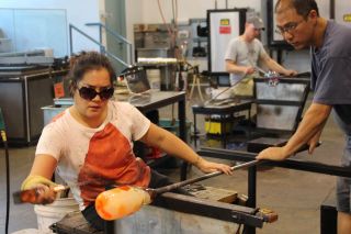 Students work with hot glass at a class in The Studio